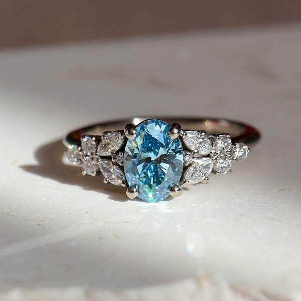 Ring with a blue diamond and white diamonds accents on a light background
