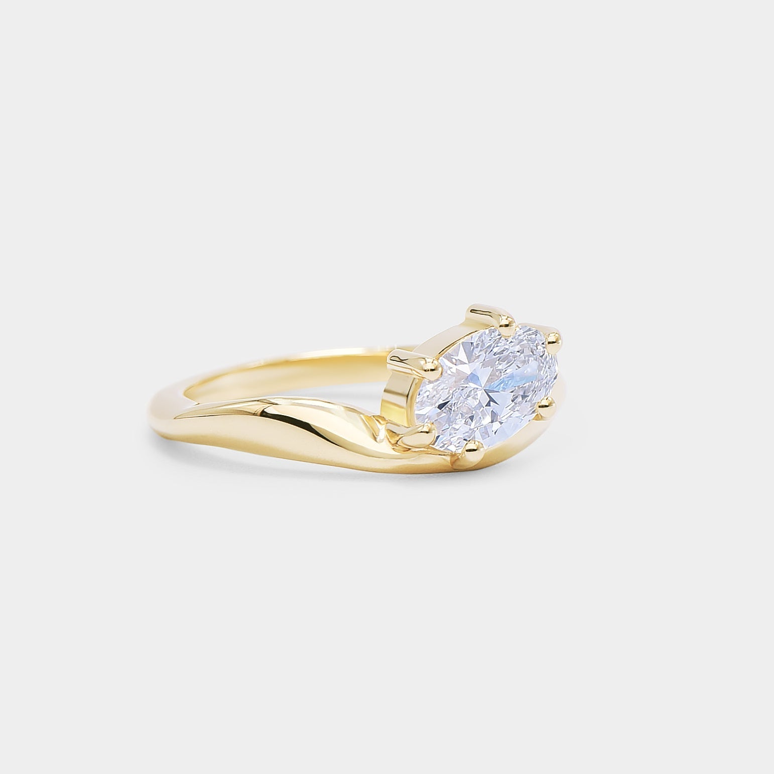 Oval diamond in a curvy sculpture smooth gold band. Dune - oval lab diamond