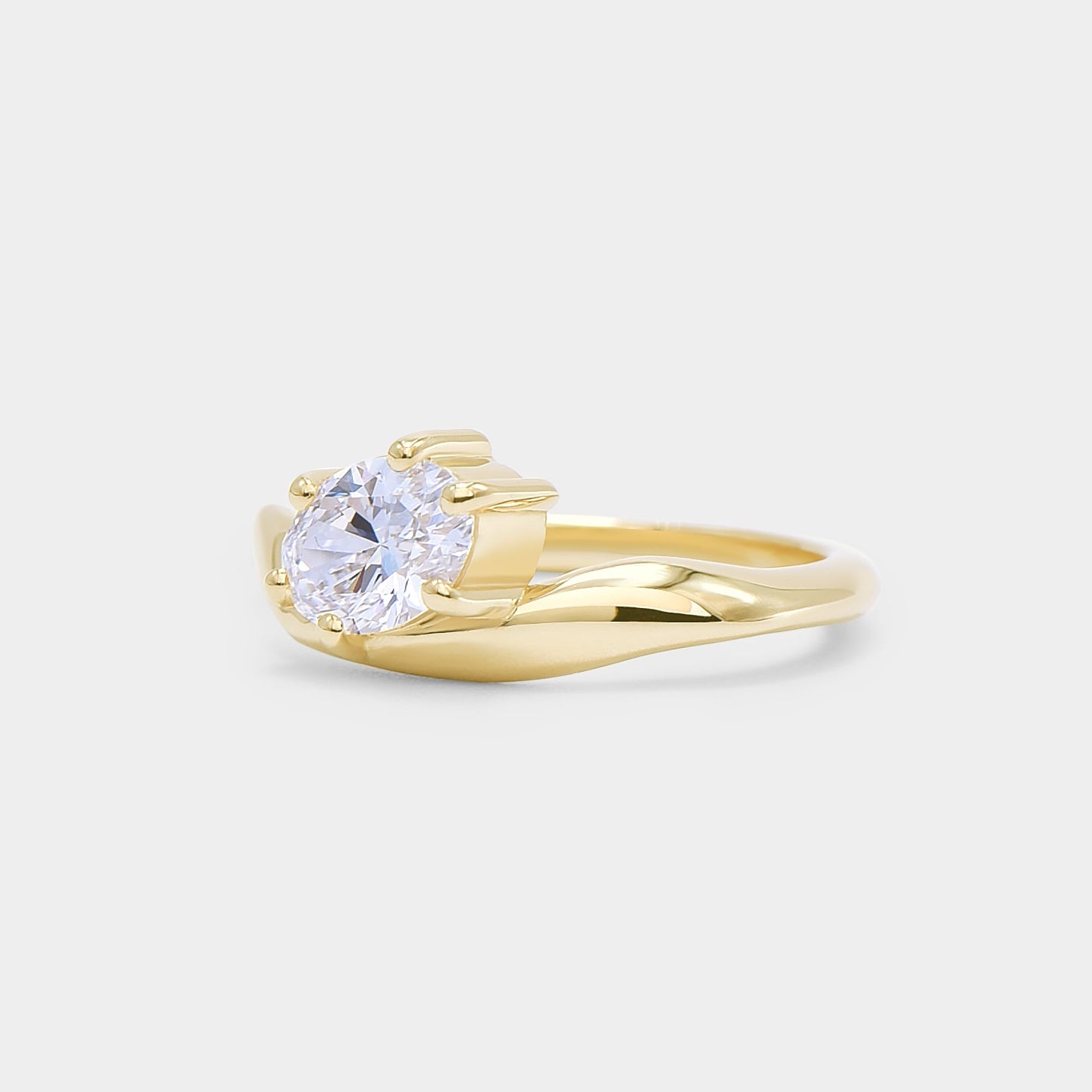 Oval diamond in a curvy sculpture smooth gold band. Dune - oval lab diamond