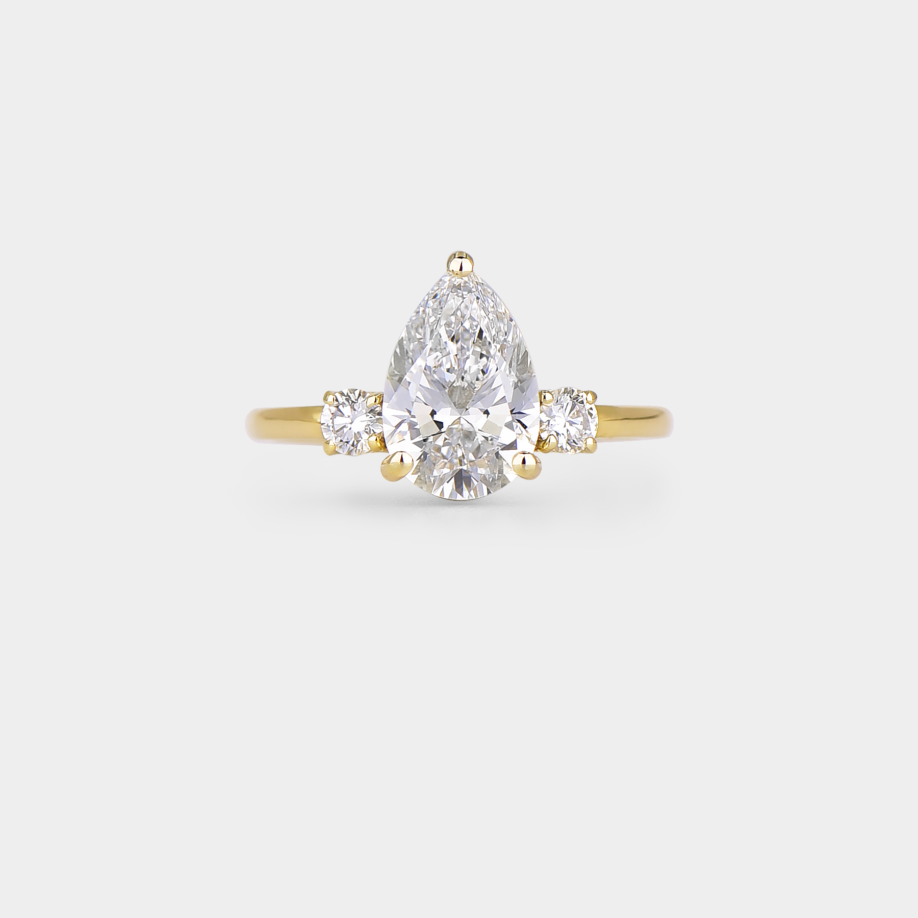 Gold ring with a pear-shaped diamond on a light gray background