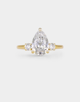 Gold ring with a pear-shaped diamond on a light gray background