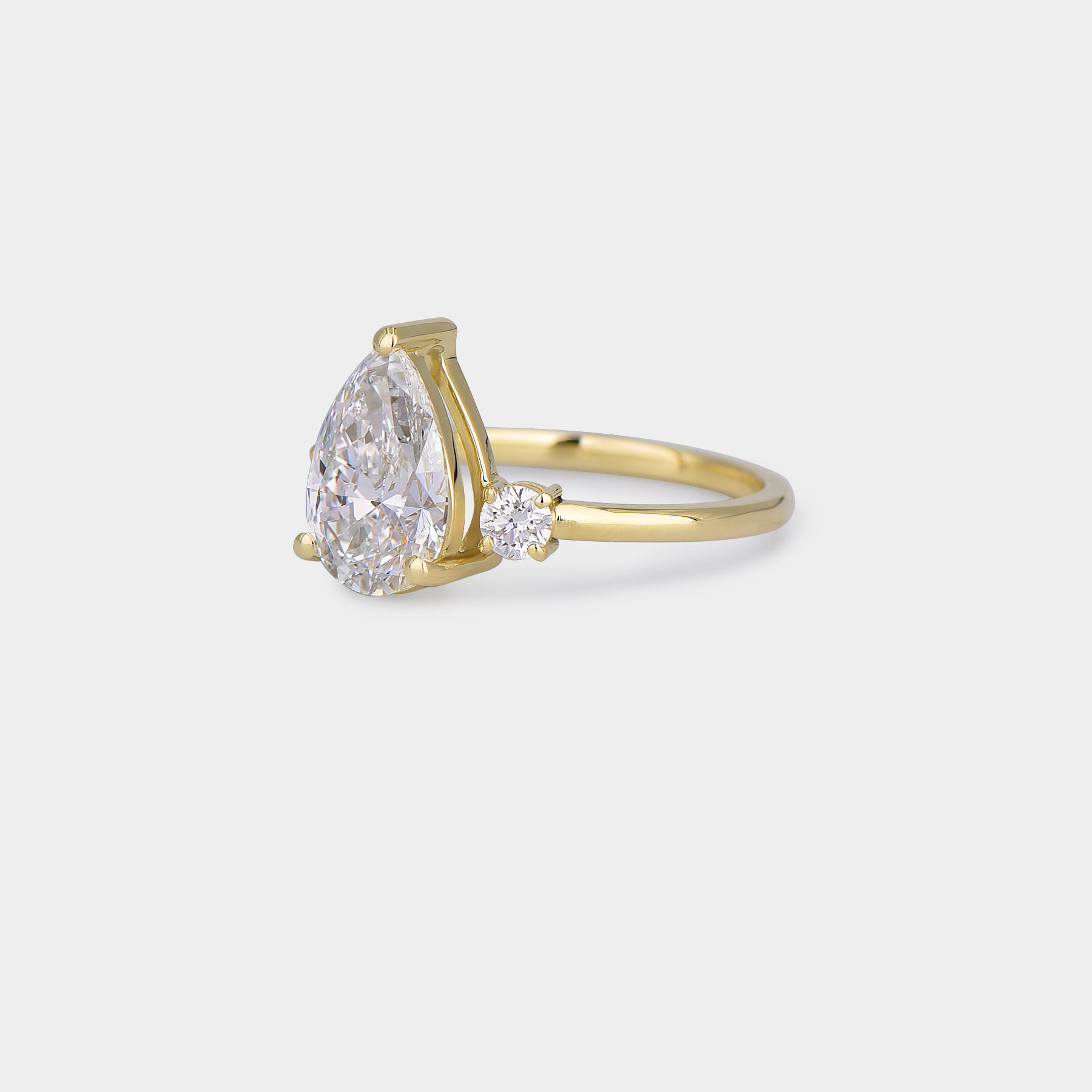 Gold ring with a pear-shaped diamond on a light gray background