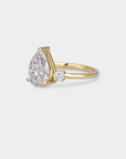 Gold ring with a pear-shaped diamond on a light gray background