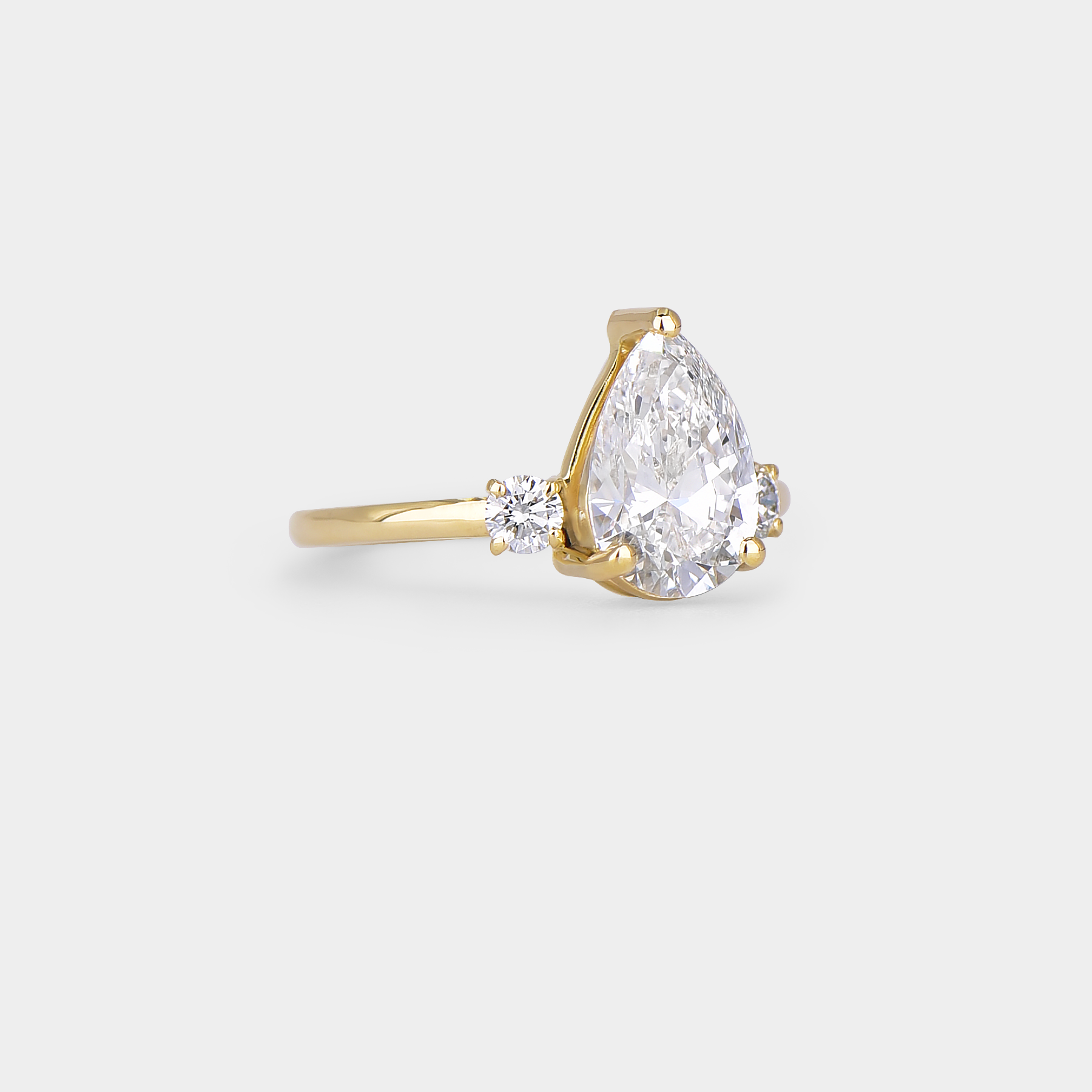 Gold ring with a pear-shaped diamond on a light gray background