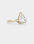 Gold ring with a pear-shaped diamond on a light gray background